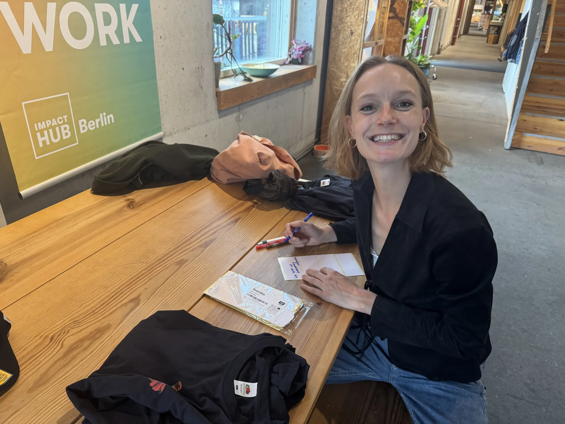 Else preparing name cards beside the Impact Hub Berlin sign
